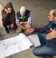 An instructor gestures toward a siteplan as students look on