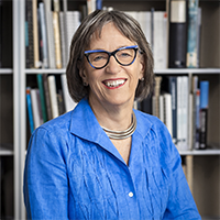 Headshot of Lucinda Sanders smiling in front of a bookcase