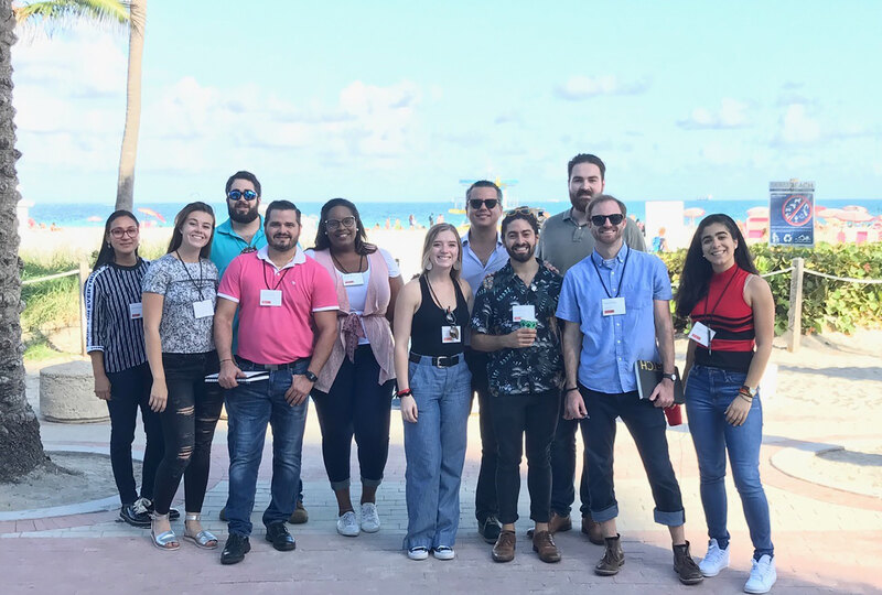 Roberto Rovira and his team pose together under a palm tree on Miami Beach