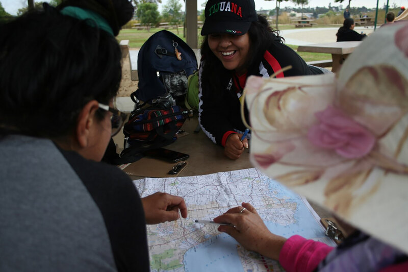 Hispanic/Latino youth gather around a map at a picnic table