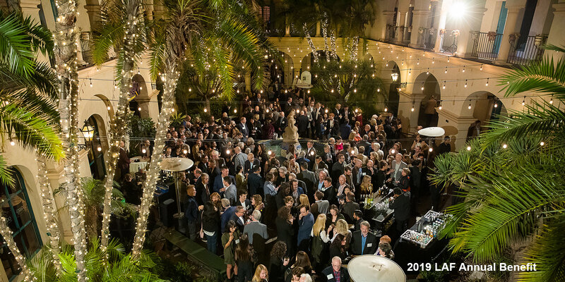 Hundreds of guests mingle in a courtyard framed by palm trees at the 2019 LAF Annual Benefit