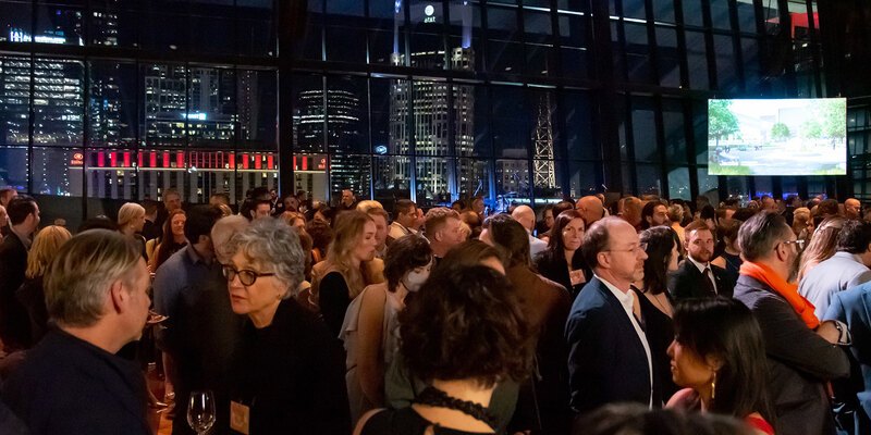 A roomful of guests catch up with a wall of windows and the Nashville skyline in the background