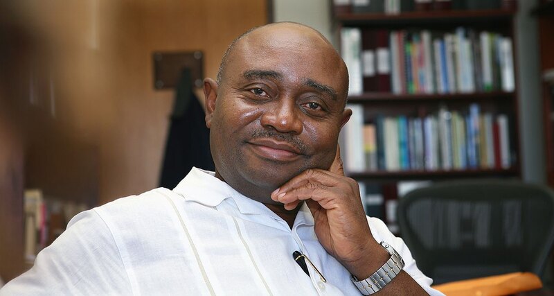 Forster Ndubisi sitting in an office with a bookshelf in the background