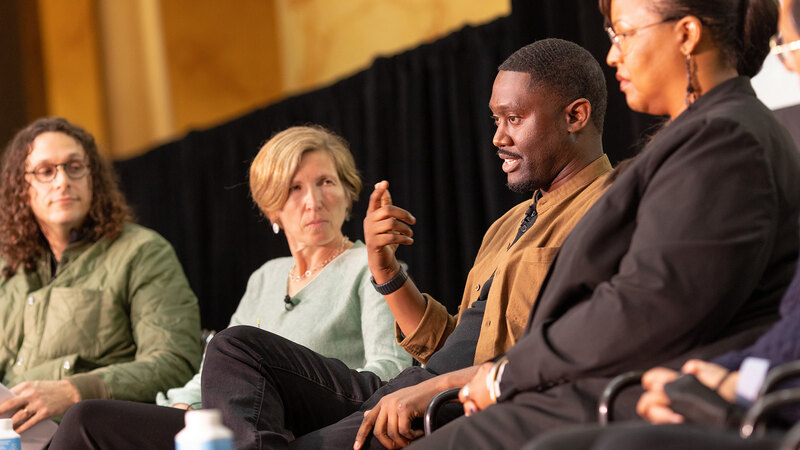 Bryan Lee gestures while making a point on stage with other panelists