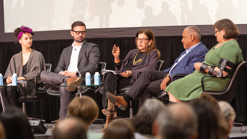 Mia Lehrer gestures while making a point on stage with other panelists