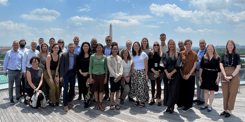 30 members of the LAF board and staff smile on a roofdeck overlooking the Washington Monument