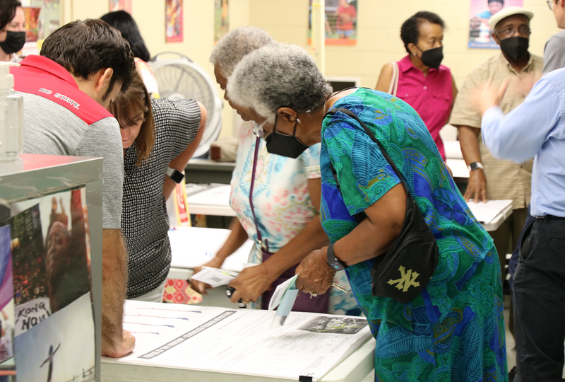 Community members gather around plans on a table at a public meeting.