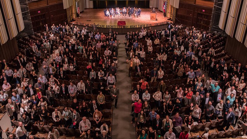 A theater of people facing up toward the photographer on the balcony