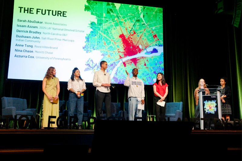 a stage with 7 individuals in front of a projected screen displaying "The Future"