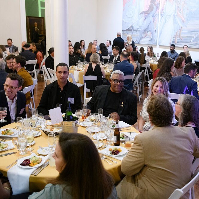 People seated at round tables conversing over dinner