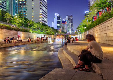 People sit by the restored Cheonggyecheon Stream in Seoul at night