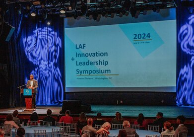LAF President Michael Grove on stage behind a podium kicking off the symposium