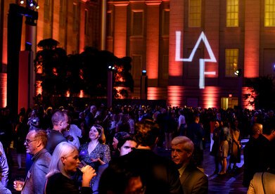 With a projection of the LAF logo on the wall in the background, attendees at LAF's 2024 Annual Benefit cluster in small groups.