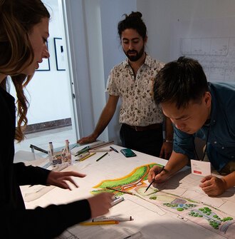 4 college students around a table working on a landscape design drawing