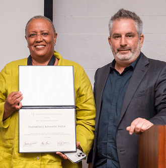 Elizabeth Kennedy stands with LAF Award Committee Chair Adam Greenspan and holds her certificate