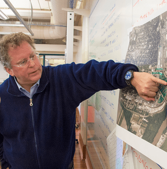 Peter Schaudt points at a map on a wall.