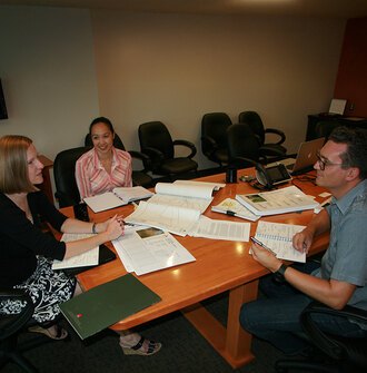 Two academic researchers meeting with a designer in an office conference room