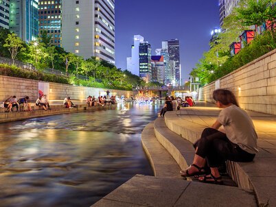 People sit by the restored Cheonggyecheon Stream in Seoul at night