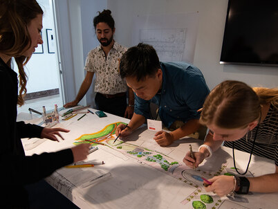 4 college students around a table working on a landscape design drawing