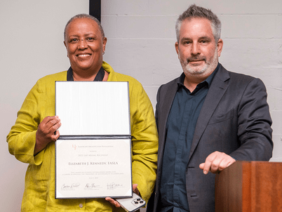 Elizabeth Kennedy stands with LAF Award Committee Chair Adam Greenspan and holds her certificate