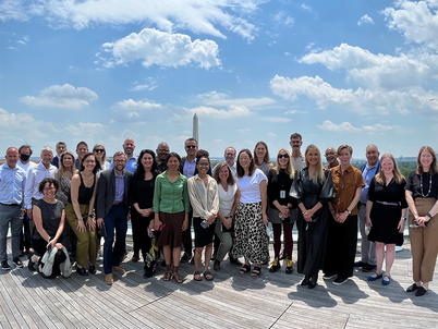 30 members of the LAF board and staff smile on a roofdeck overlooking the Washington Monument
