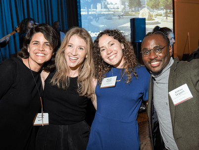 A group of four Annual Benefit attendees pose smiling in front of the stage