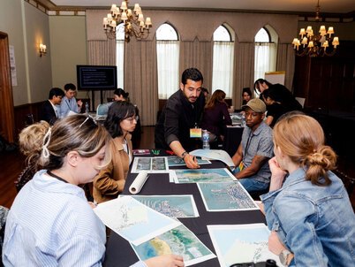An instructor pointing out specifics on a page to a table of students. 