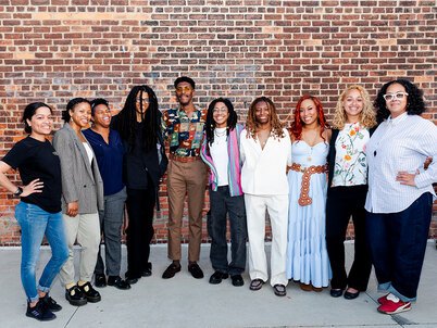 A group of eight Ignite students and two program facilitators smiling in front of a brick wall
