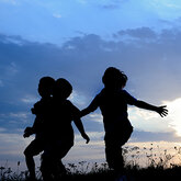 A silhouette of kids running on a hill in the evening sun
