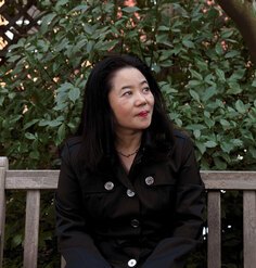 A portrait of Noriko Maeda sitting on a bench