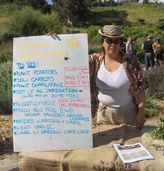 Jennifer Gorospe poses in an urban garden with a to-do list of gardening activities