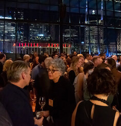 A roomful of guests catch up with a wall of windows and the Nashville skyline in the background