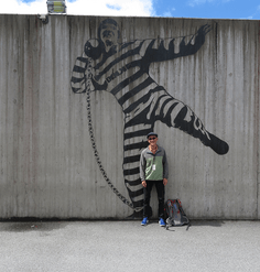 Daniel Winterbottom stands in front of a mural on a prison wall.