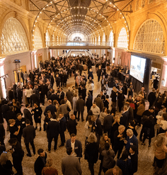 A large crowd of guests mingle under the lighted arches of the San Francisco Ferry Building's Grand Hall
