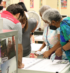 People look at plans on a table at a public meeting.