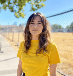 Kimberly Garza stands on a sidewalk in a yellow Atlas Lab shirt.