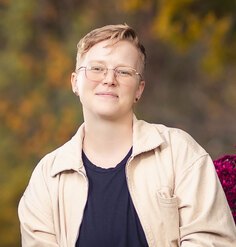 headshot style photo of a person in their 30s with short blonde hair and glasses