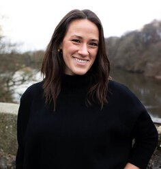 A photo of Betsy Peterson standing in front of a river in winter