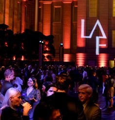 With a projection of the LAF logo on the wall in the background, attendees at LAF's 2024 Annual Benefit cluster in small groups.