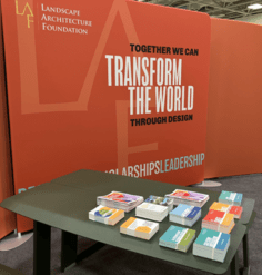 image of an orange expo booth with a table of stacked postcards and phamplets